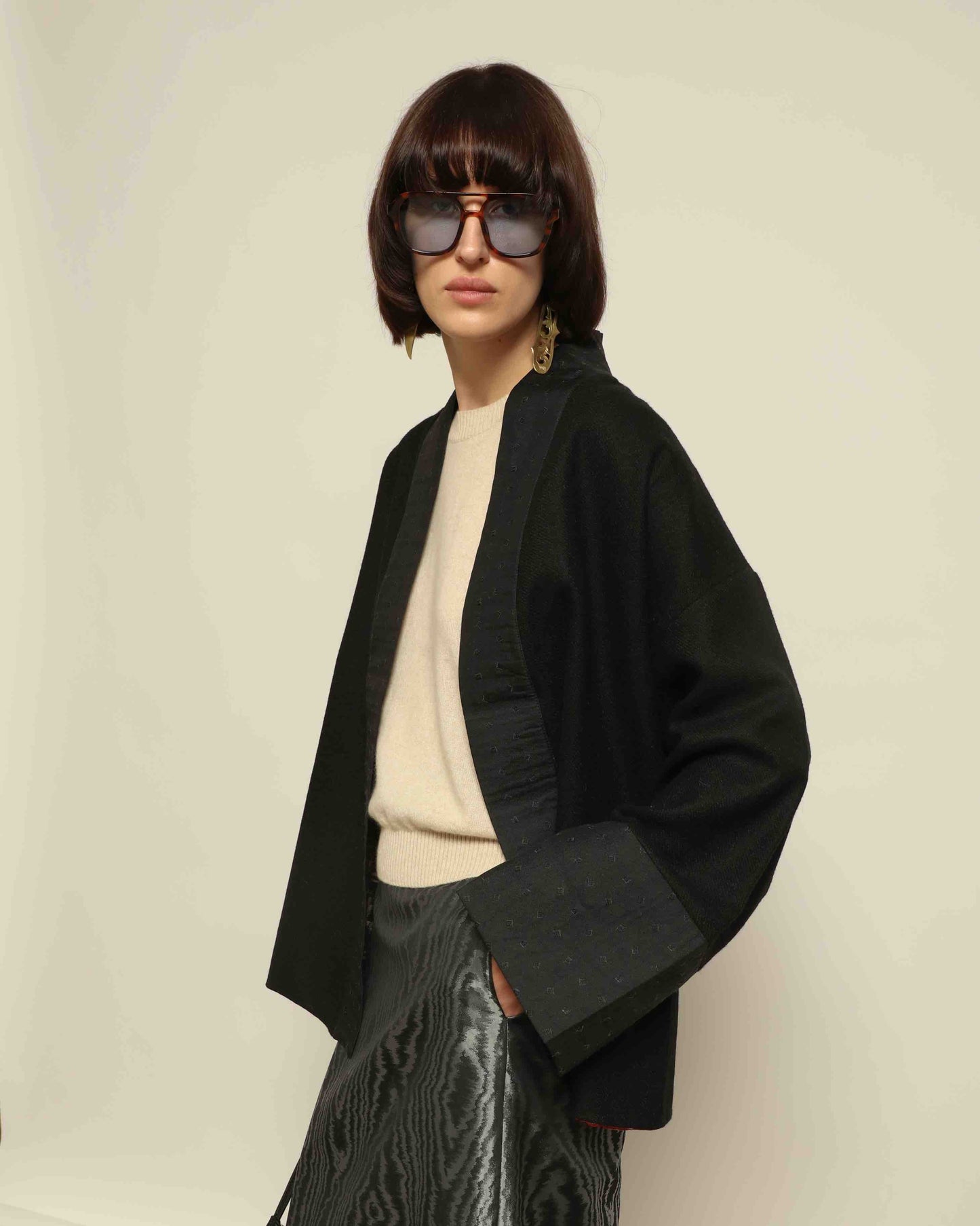 The model is wearing the Obidi Midnight Kantha Jacket in pure black, made of wool with a silk collar and Kantha silk lining, a timeless and versatile piece.