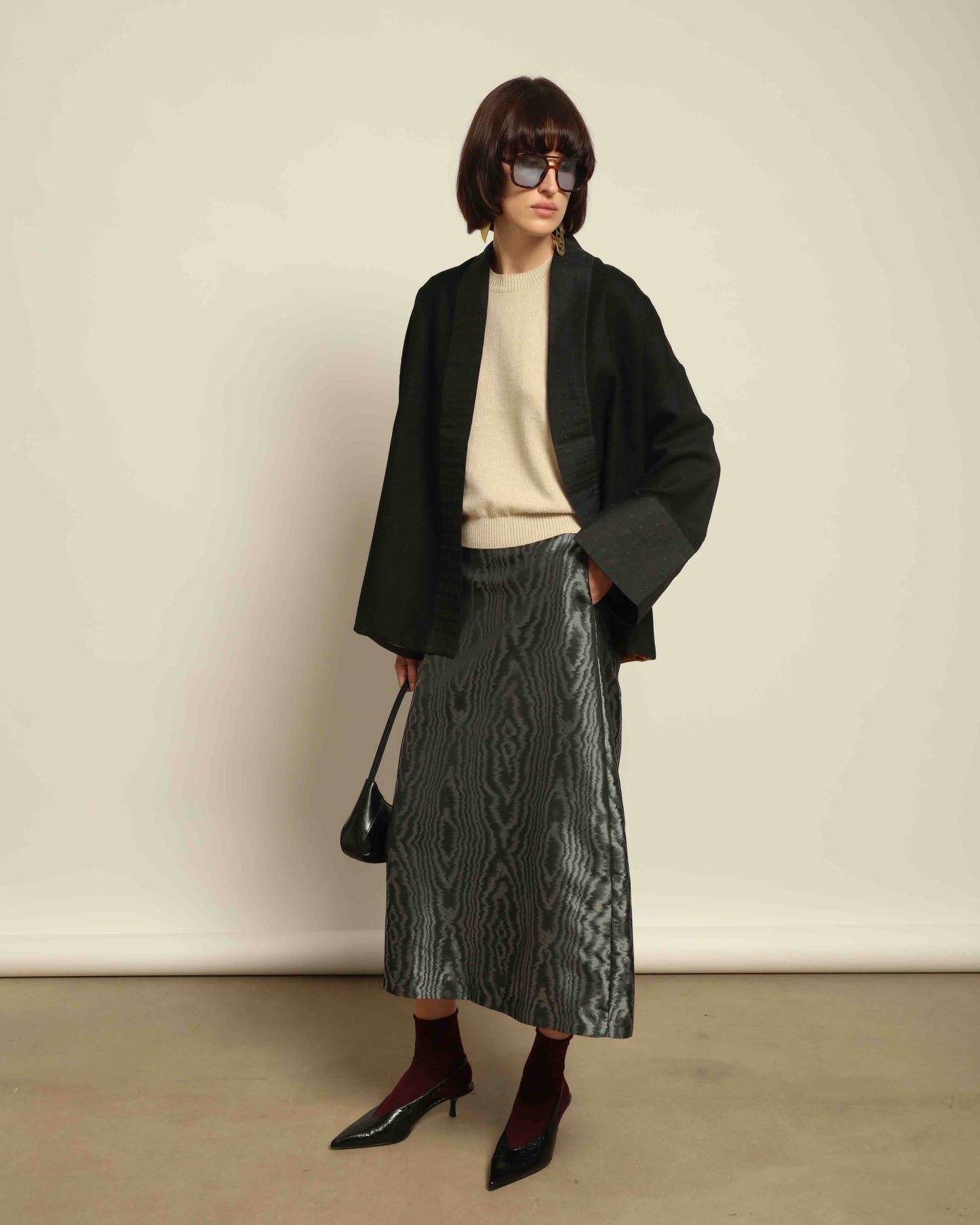The model is wearing the Obidi Midnight Kantha Jacket in pure black, made of wool with a silk collar and Kantha silk lining, a timeless and versatile piece.
