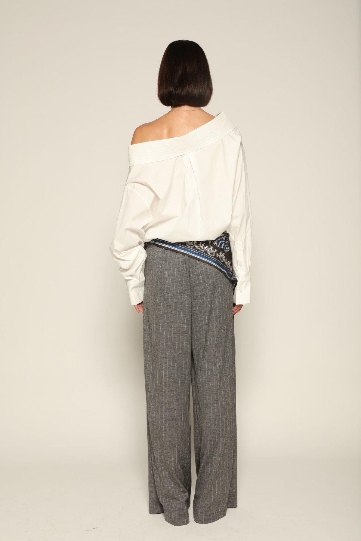 Model wearing a luxury off-shoulder woven cotton bodysuit by Abadia from the House of Nomad Stories collection featuring tailored stitching, structured fit and minimalist elegant design.