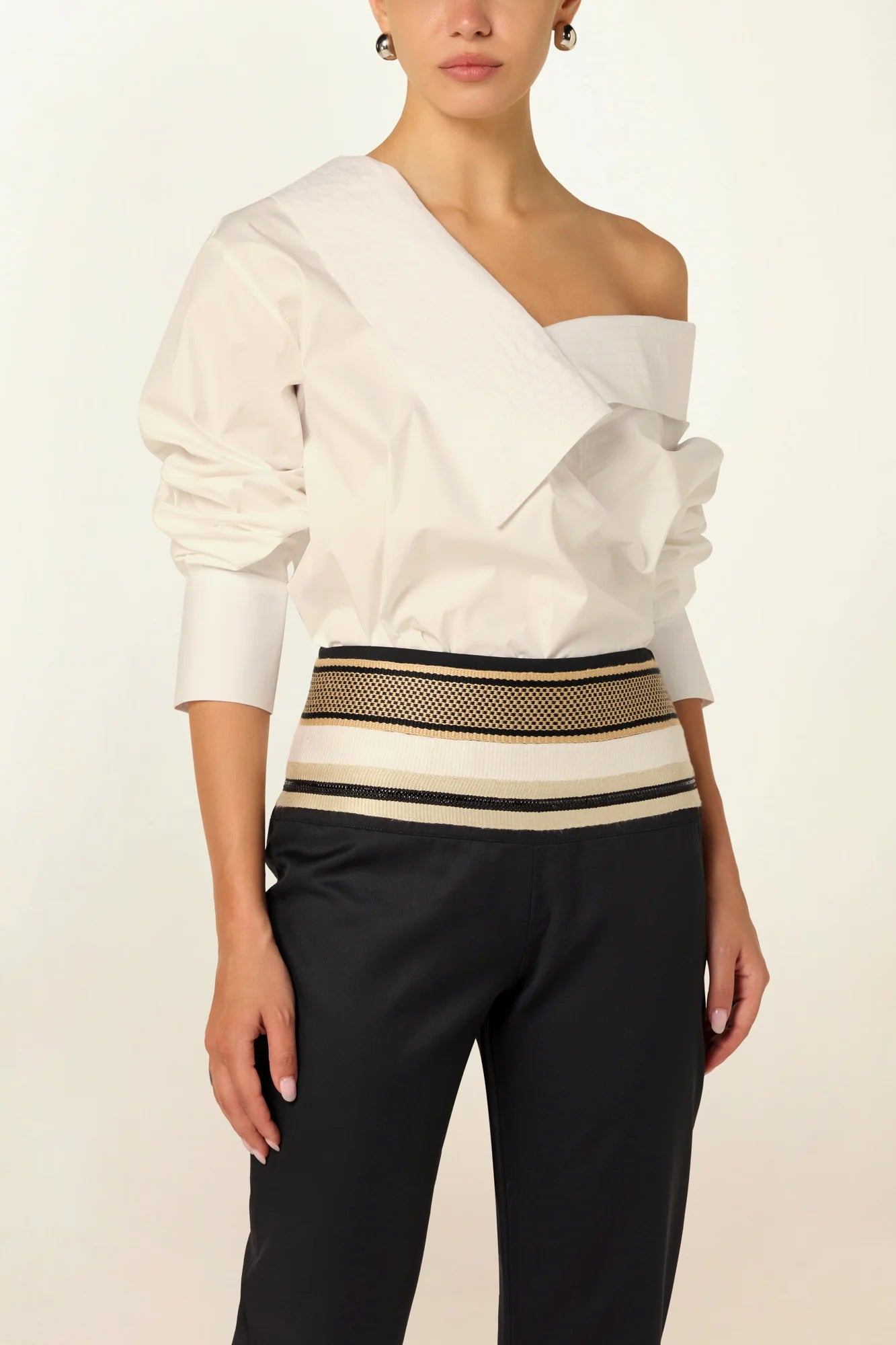 Model wearing a luxury off-shoulder woven cotton bodysuit by Abadia from the House of Nomad Stories collection featuring tailored stitching, structured fit and minimalist elegant design.
