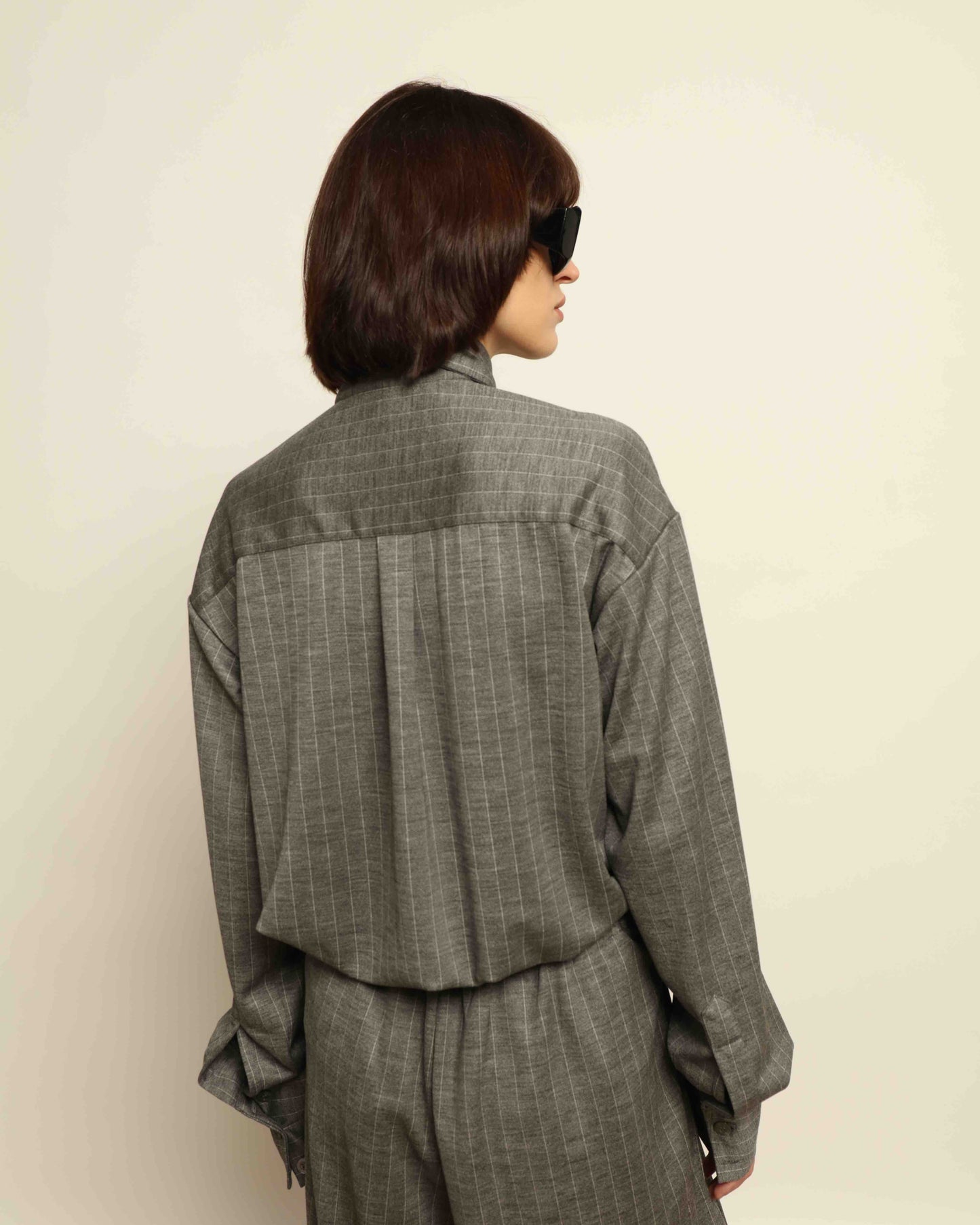 Model is wearing the Oscar Pinstriped Grey Jersey Shirt by House of Woven Stories, crafted in Italy from a merino wool and silk blend with subtle grey stripes and a tailored silhouette.