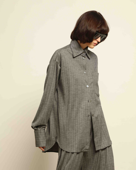 Model is wearing the Oscar Pinstriped Grey Jersey Shirt by House of Woven Stories, crafted in Italy from a merino wool and silk blend with subtle grey stripes and a tailored silhouette.