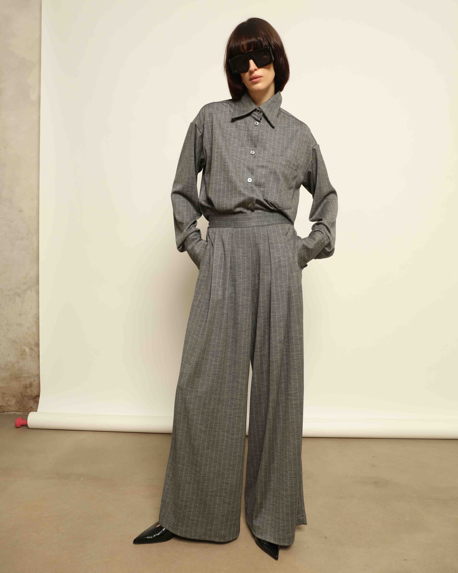 Model is wearing the Oscar Pinstriped Grey Jersey Shirt by House of Woven Stories, crafted in Italy from a merino wool and silk blend with subtle grey stripes and a tailored silhouette.