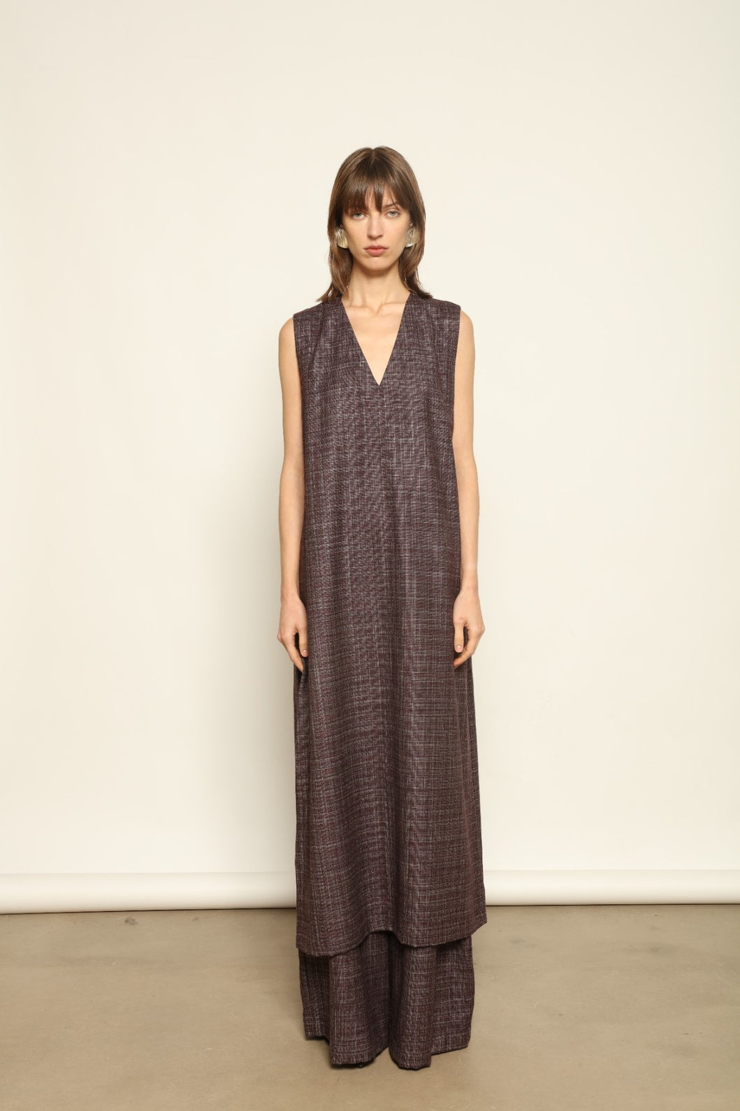 Model is wearing the Parigi Burgundy Lana Trousers by House of Woven Stories – Italian-tailored trousers crafted from a luxurious blend of merino wool, silk, and linen, featuring front pleats, side pockets, and a relaxed yet elegant burgundy silhouette.