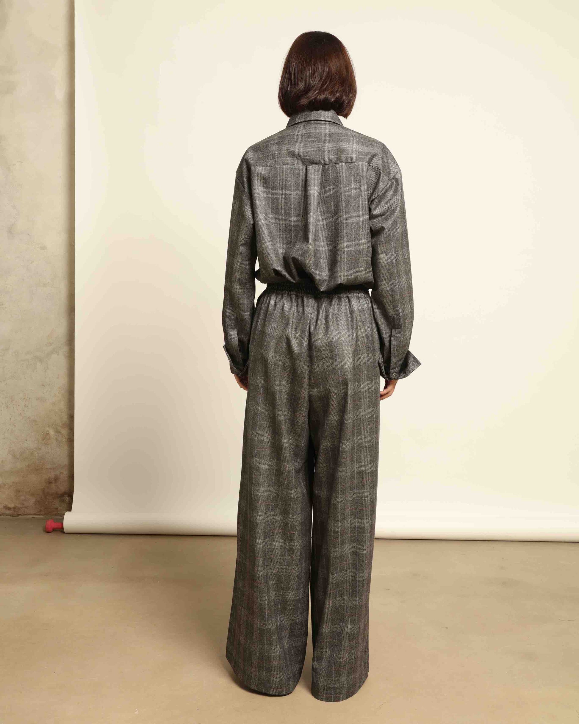 Model is wearing the Parigi Grey Check Trousers by House of Woven Stories, featuring a refined grey check pattern and a tailored silhouette, handcrafted in Piedmont, Italy.