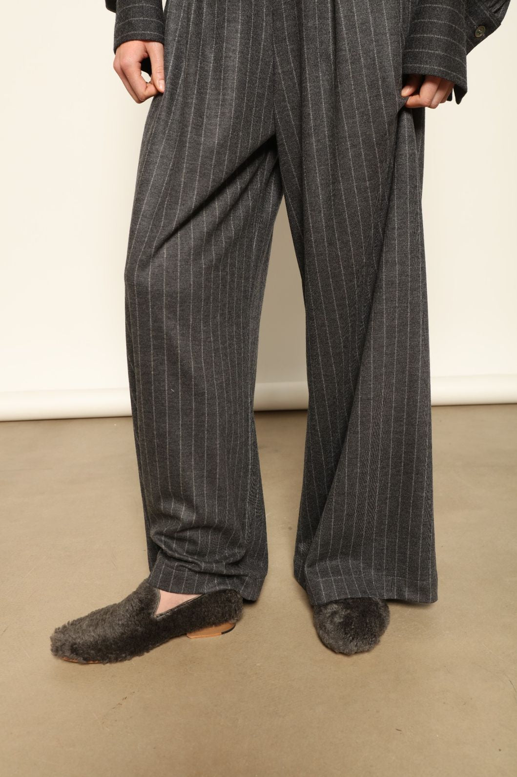 Model wearing Parigi Trousers in Double Jersey Striped Grey and White by House of Woven Stories, part of the curated selection, made in Italy from 100% Merino wool, featuring soft double jersey texture and elegant striped design for refined comfort and timeless style.