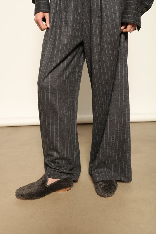 Model wearing Parigi Trousers in Double Jersey Striped Grey and White by House of Woven Stories, part of the curated selection, made in Italy from 100% Merino wool, featuring soft double jersey texture and elegant striped design for refined comfort and timeless style.