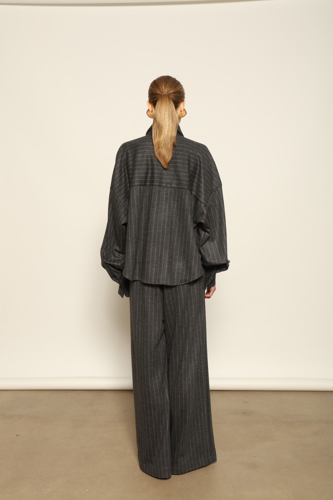 Model wearing Parigi Trousers in Double Jersey Striped Grey and White by House of Woven Stories, part of the curated selection, made in Italy from 100% Merino wool, featuring soft double jersey texture and elegant striped design for refined comfort and timeless style.