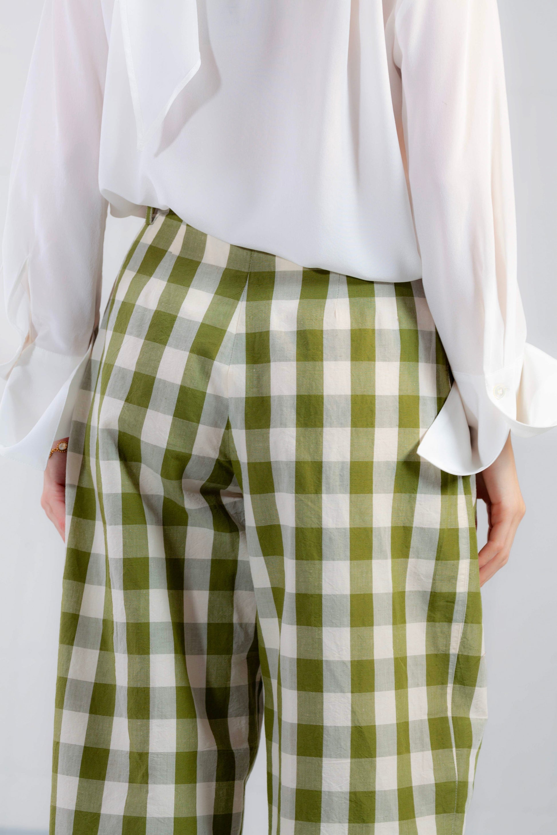 Model is wearing the Pine Checked Trousers by Balia 8.22, handcrafted in Italy from cotton and linen, featuring a relaxed straight-leg fit with pine green and white check pattern.