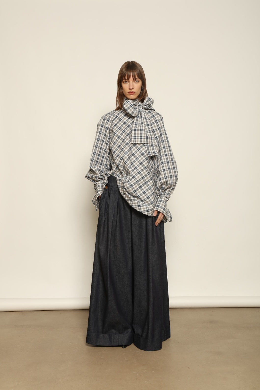 Model is wearing the Regula Maxi Check Popeline Cotton Blouse by House of Woven Stories, crafted from crisp poplin cotton in an oversized check pattern with a waist tie and buttoned cuffs.
