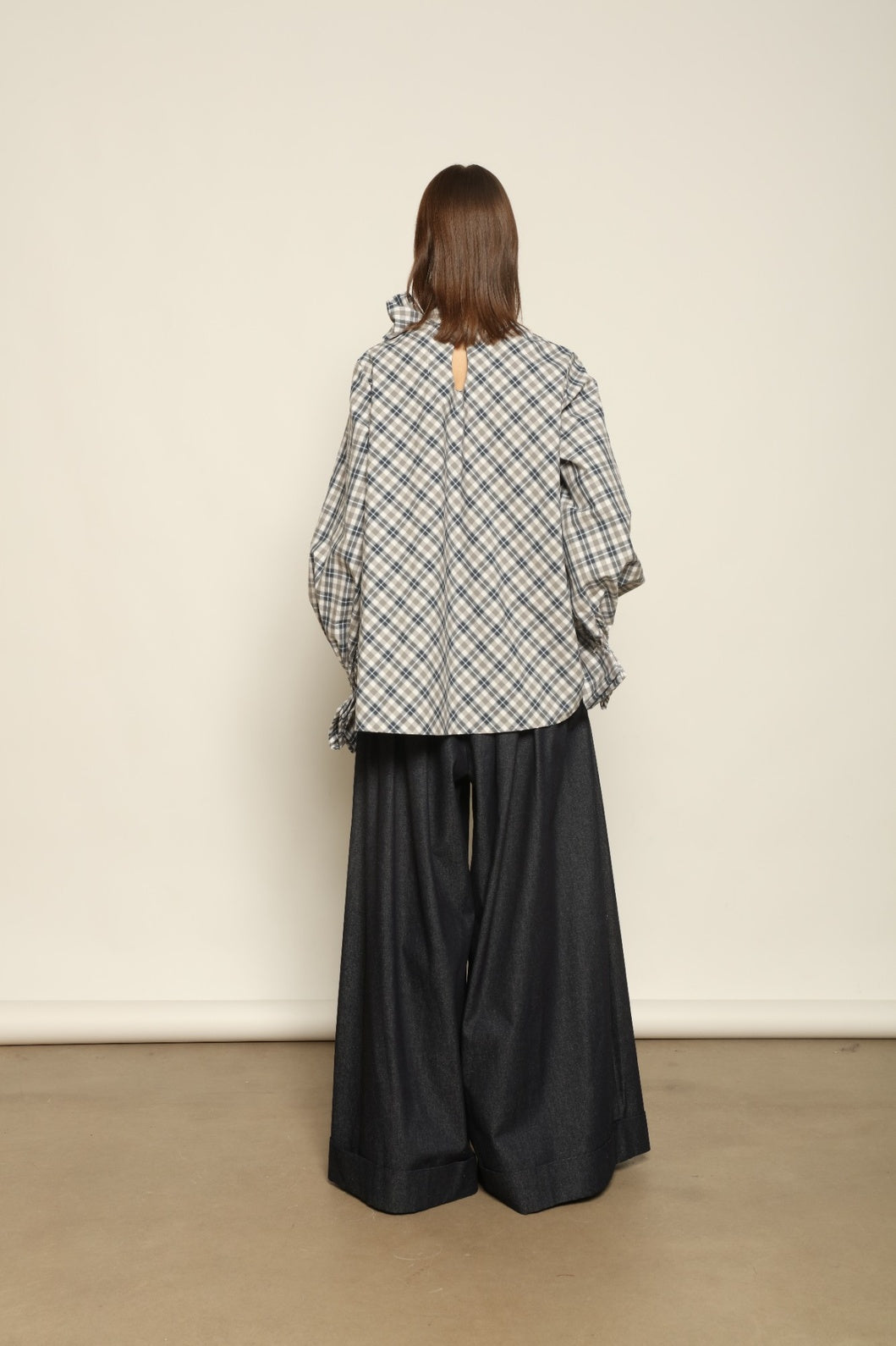 Model is wearing the Regula Maxi Check Popeline Cotton Blouse by House of Woven Stories, crafted from crisp poplin cotton in an oversized check pattern with a waist tie and buttoned cuffs.