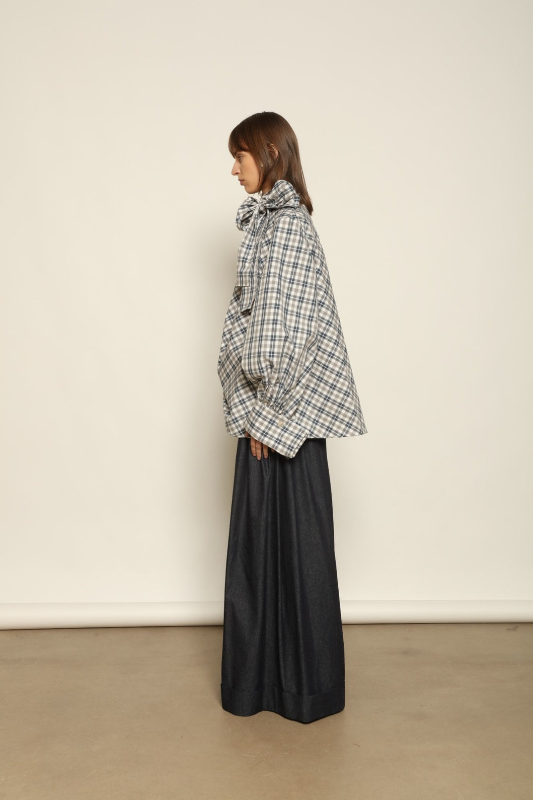 Model is wearing the Regula Maxi Check Popeline Cotton Blouse by House of Woven Stories, crafted from crisp poplin cotton in an oversized check pattern with a waist tie and buttoned cuffs.