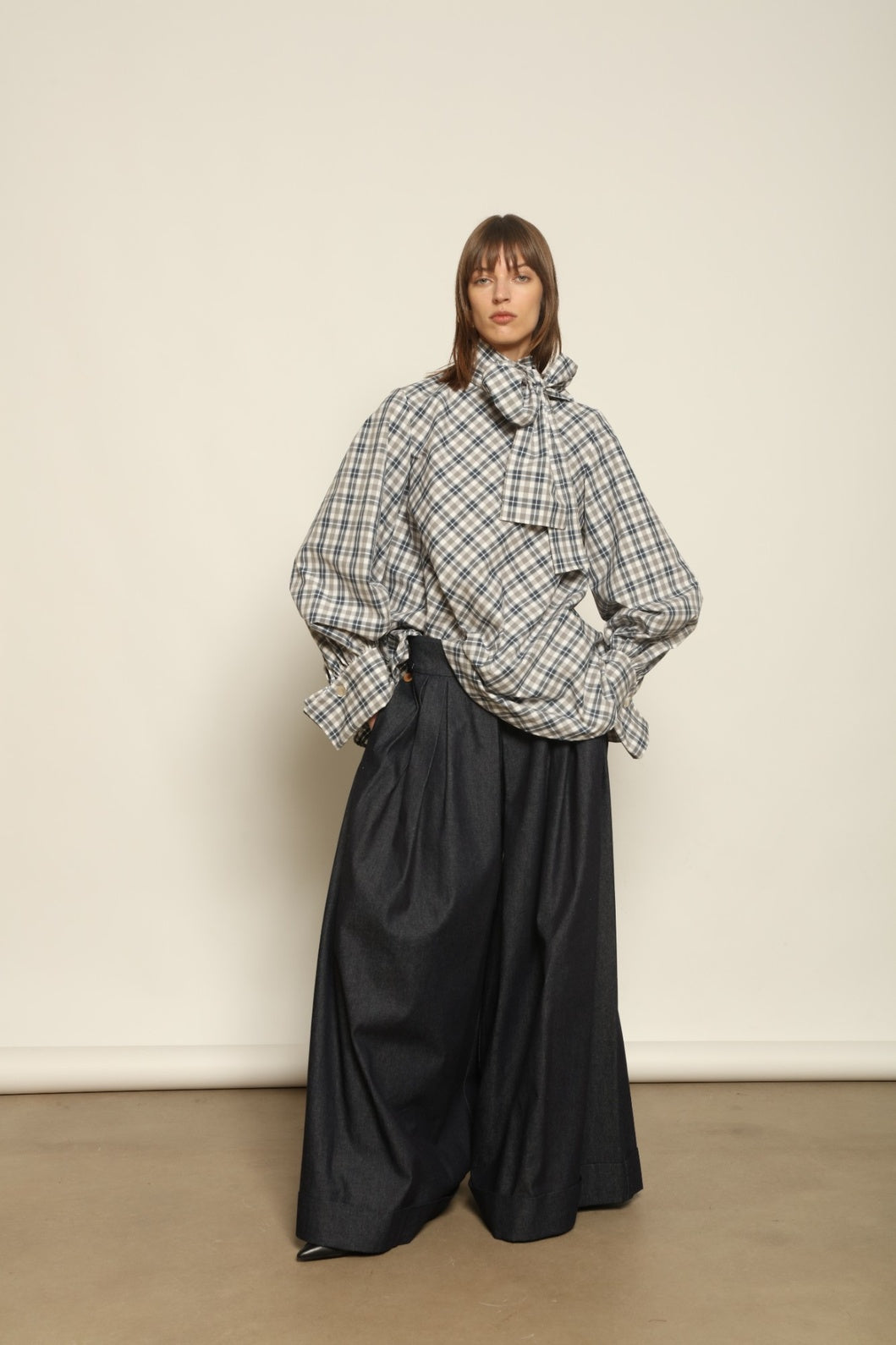 Model is wearing the Regula Maxi Check Popeline Cotton Blouse by House of Woven Stories, crafted from crisp poplin cotton in an oversized check pattern with a waist tie and buttoned cuffs.