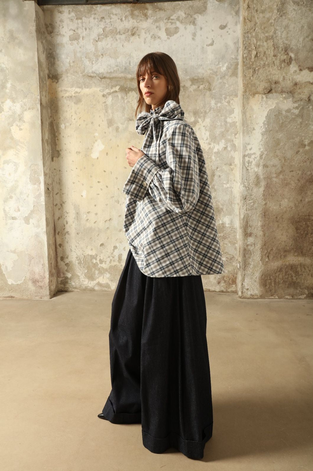 Model is wearing the Regula Maxi Check Popeline Cotton Blouse by House of Woven Stories, crafted from crisp poplin cotton in an oversized check pattern with a waist tie and buttoned cuffs.