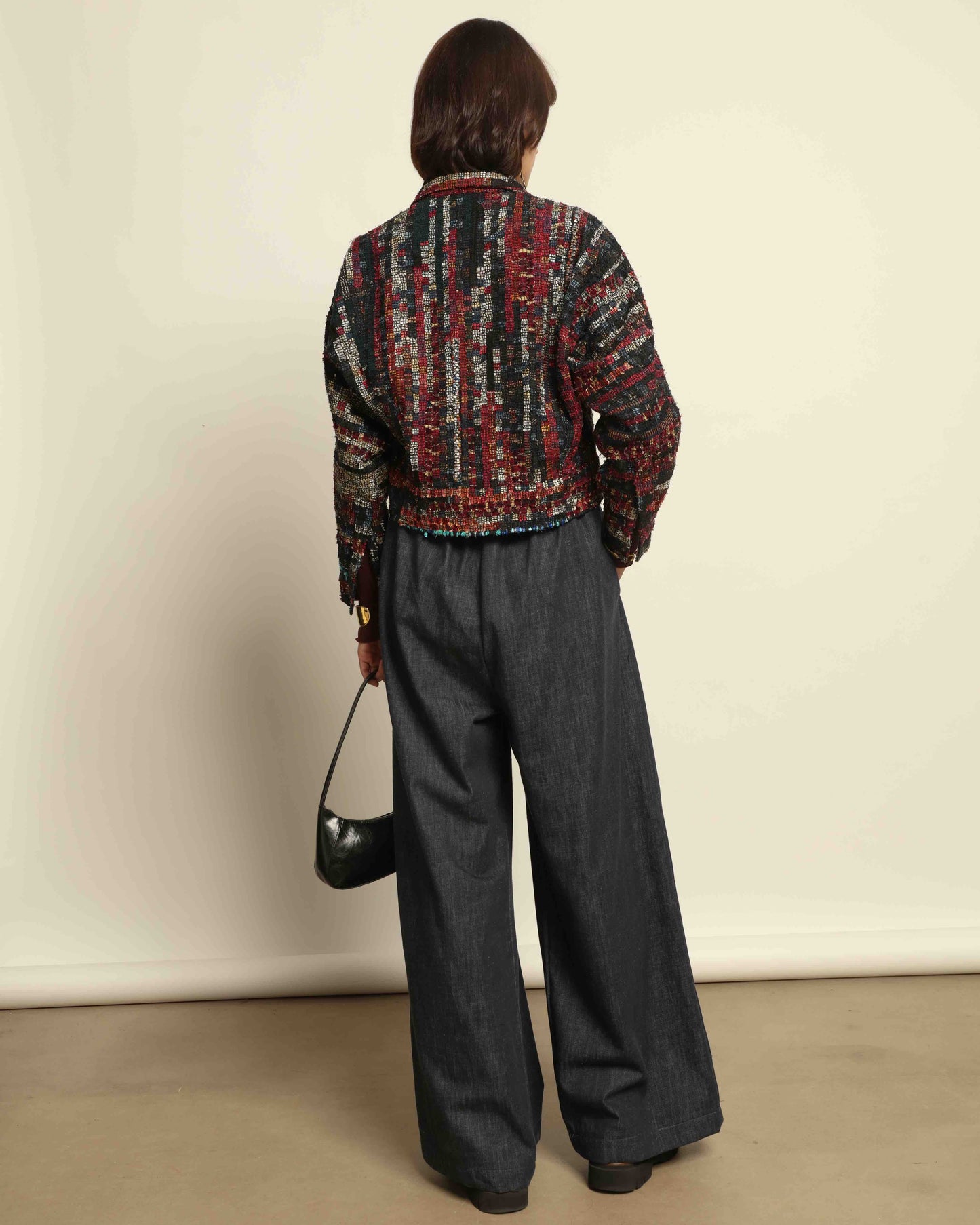 Model is wearing the Rewoven Hand-loomed Bomber by Paiwand, an upcycled unisex jacket crafted from handwoven organic cotton off-cuts with unique color and design variations.