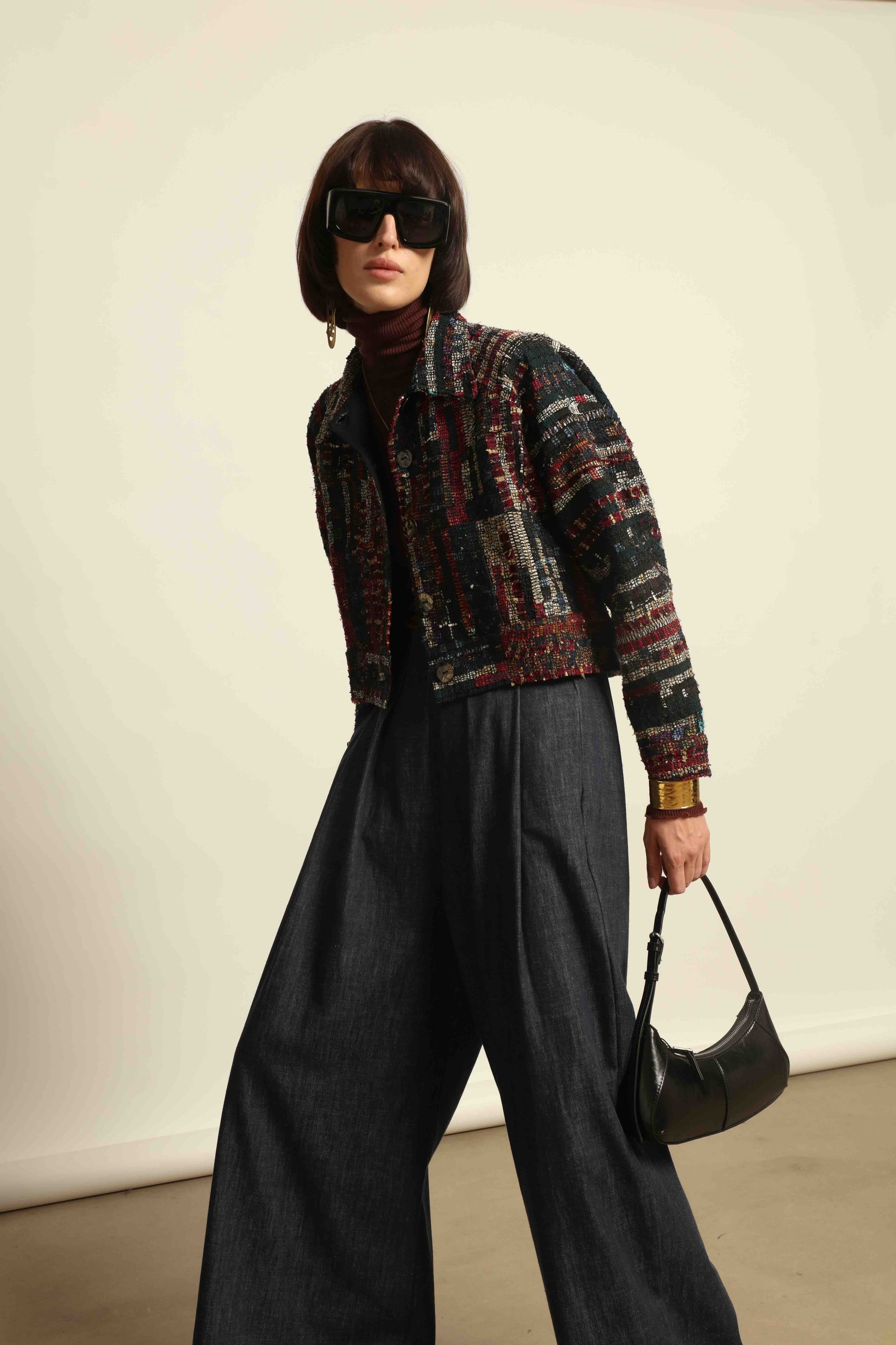 Model is wearing the Rewoven Hand-loomed Bomber by Paiwand, an upcycled unisex jacket crafted from handwoven organic cotton off-cuts with unique color and design variations.
