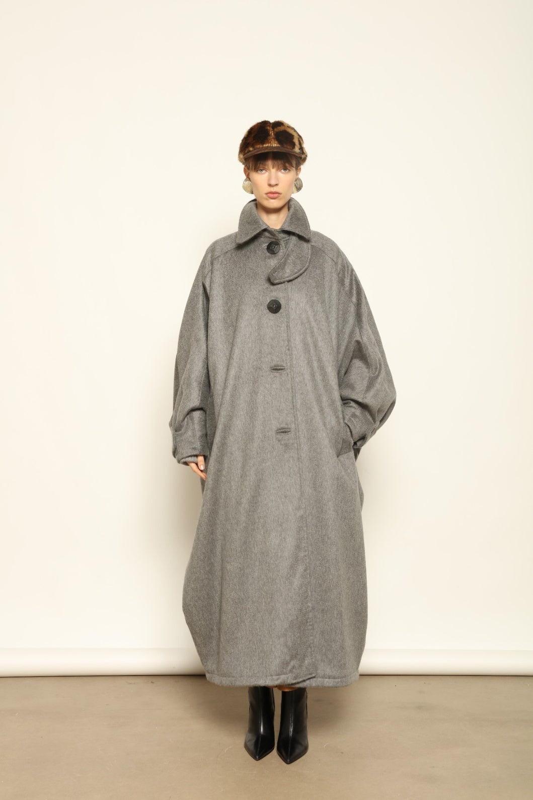 Model is wearing the Ryadh Long Coat in flannel grey by House of Woven Stories, made from merino wool and cashmere with silk lining and vintage 1960s buttons.
