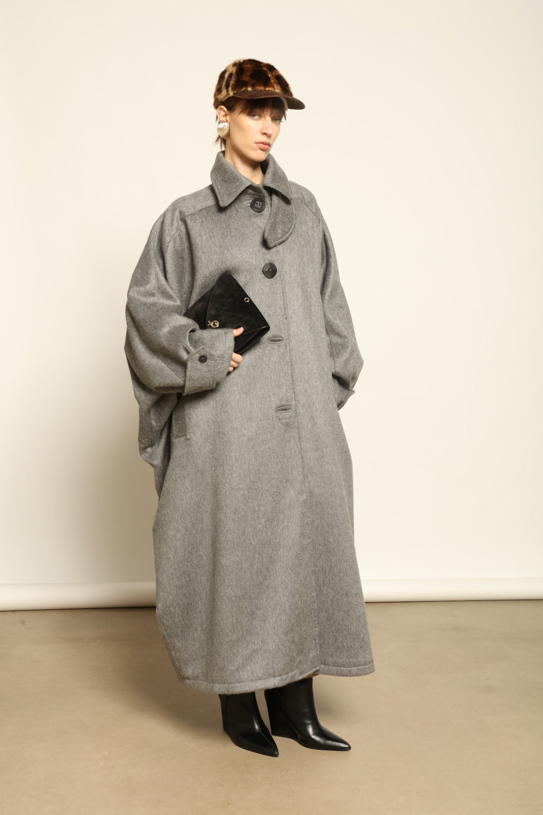 Model is wearing the Ryadh Long Coat in flannel grey by House of Woven Stories, made from merino wool and cashmere with silk lining and vintage 1960s buttons.