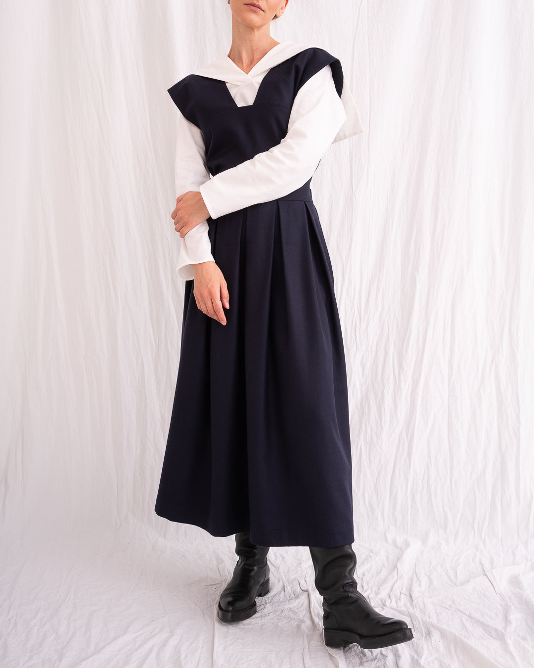 Model is wearing the Sarafan Pure New Wool Dress by Les Vacances d’Irina, a handmade navy merino wool dress with A-line silhouette, tie-back detail, horn buttons, and side pockets, available at House of Woven Stories.