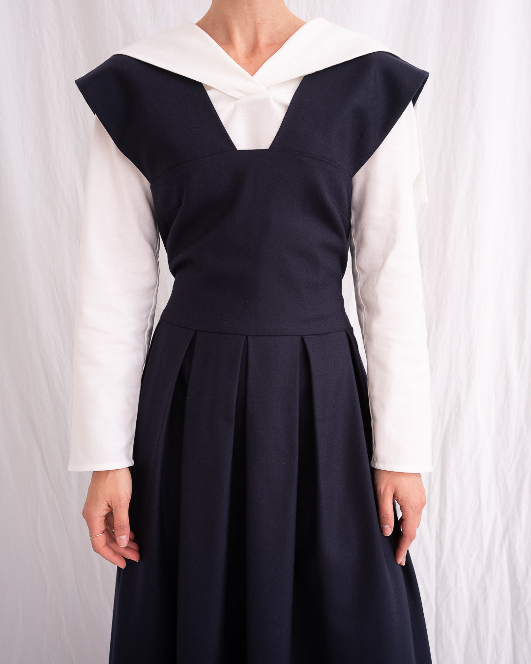 Model is wearing the Sarafan Pure New Wool Dress by Les Vacances d’Irina, a handmade navy merino wool dress with A-line silhouette, tie-back detail, horn buttons, and side pockets, available at House of Woven Stories.
