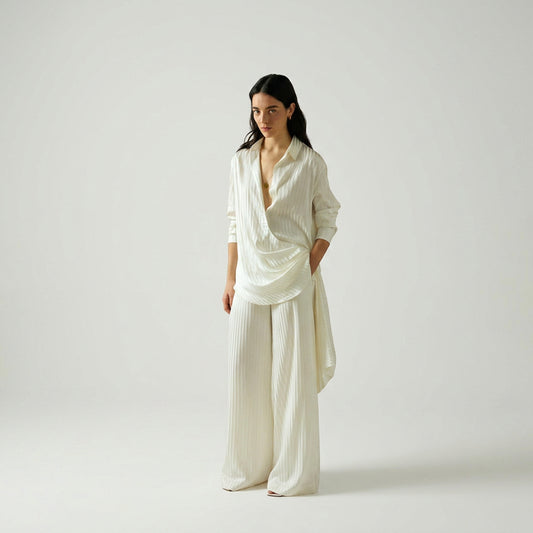Elegant model wearing a luxury white striped silk blouse by Abadia with scarf drape detailing, featuring a fluid silhouette, classic collar, and refined minimalist styling.