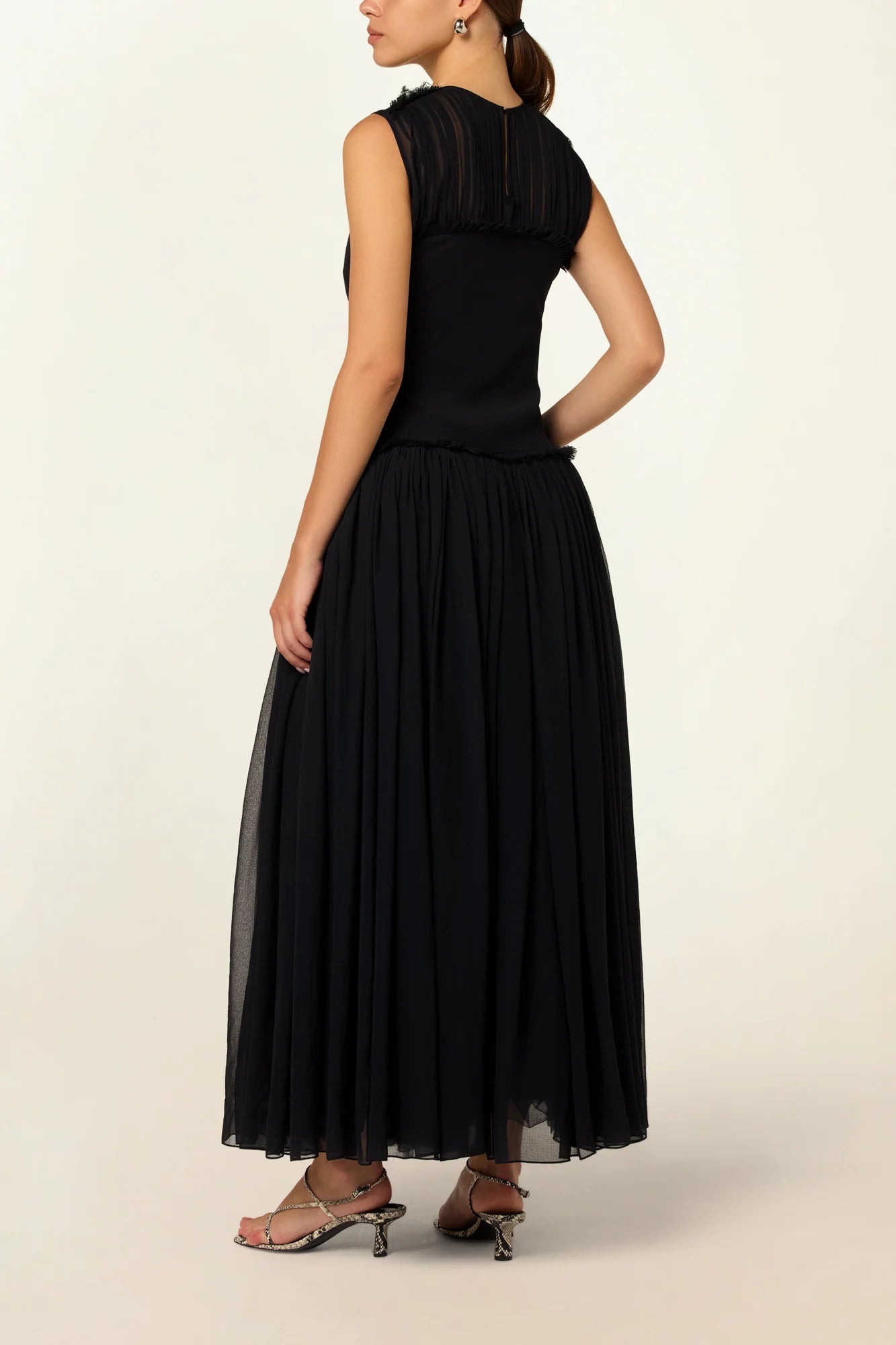 Model wearing a black silk Sera Dress by Abadia from the House of Nomad Stories collection, featuring a fitted bodice and fluid midi skirt with an elegant lightweight drape.