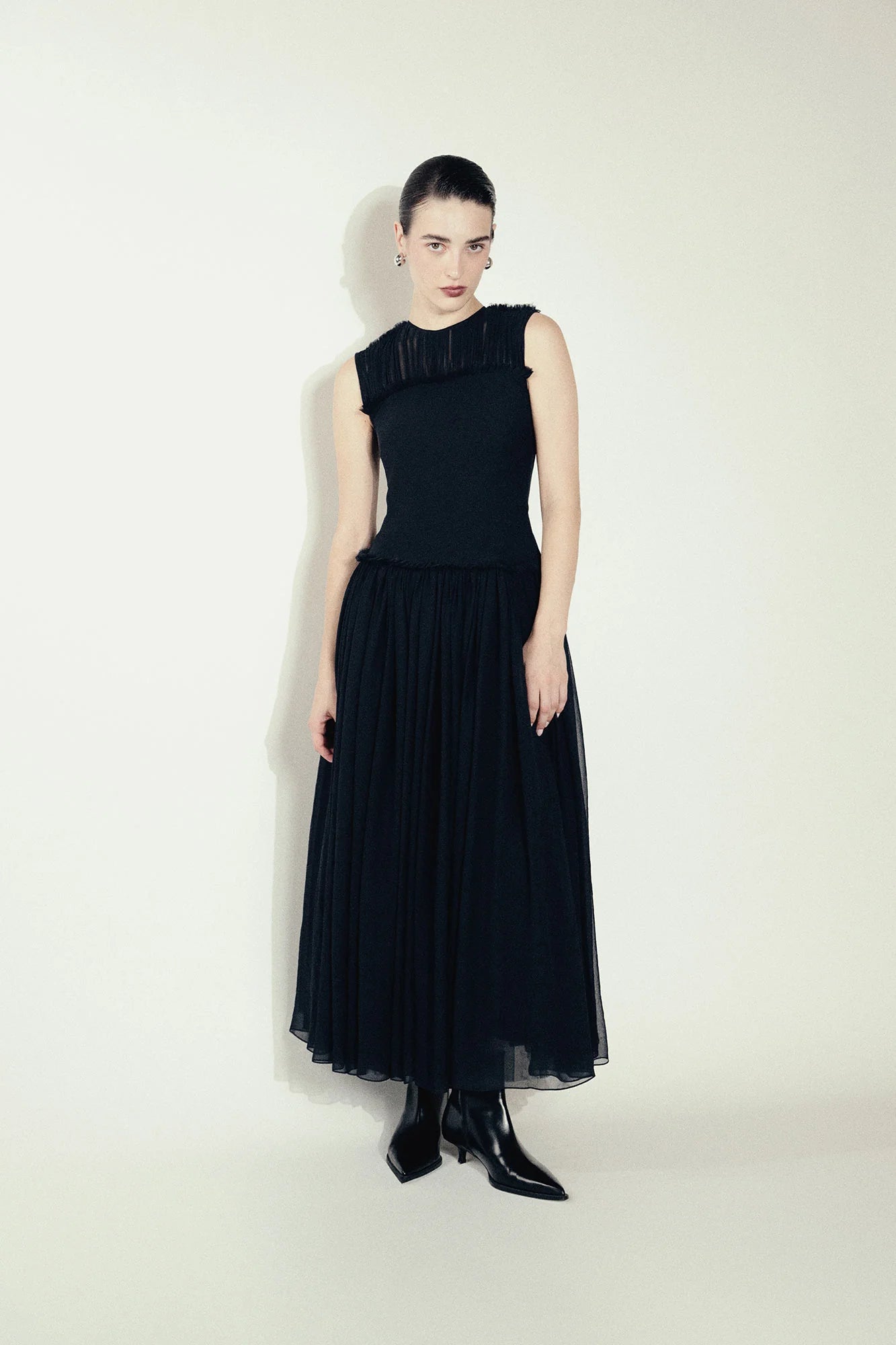 Model wearing a black silk Sera Dress by Abadia from the House of Nomad Stories collection, featuring a fitted bodice and fluid midi skirt with an elegant lightweight drape.