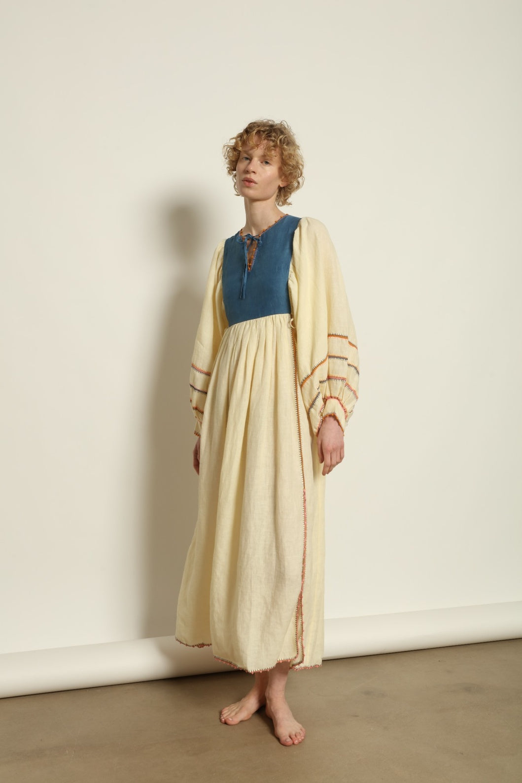Model is wearing the Serafina Blue Linen Dress by Supernaturae x HONS, crafted in structured linen blended with hand-spun silk, featuring deep indigo botanical dye tones inspired by the sea. This sustainable slow fashion piece includes delicate hand-crochet edges and natural organic variations unique to each garment. Made in small-batch production in Mexico using ancestral techniques, part of the House of Woven Stories selection