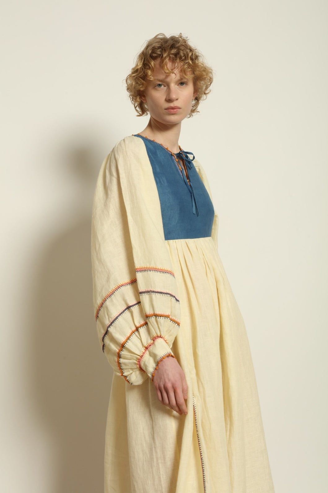 Model is wearing the Serafina Blue Linen Dress by Supernaturae x HONS, crafted in structured linen blended with hand-spun silk, featuring deep indigo botanical dye tones inspired by the sea. This sustainable slow fashion piece includes delicate hand-crochet edges and natural organic variations unique to each garment. Made in small-batch production in Mexico using ancestral techniques, part of the House of Woven Stories selection