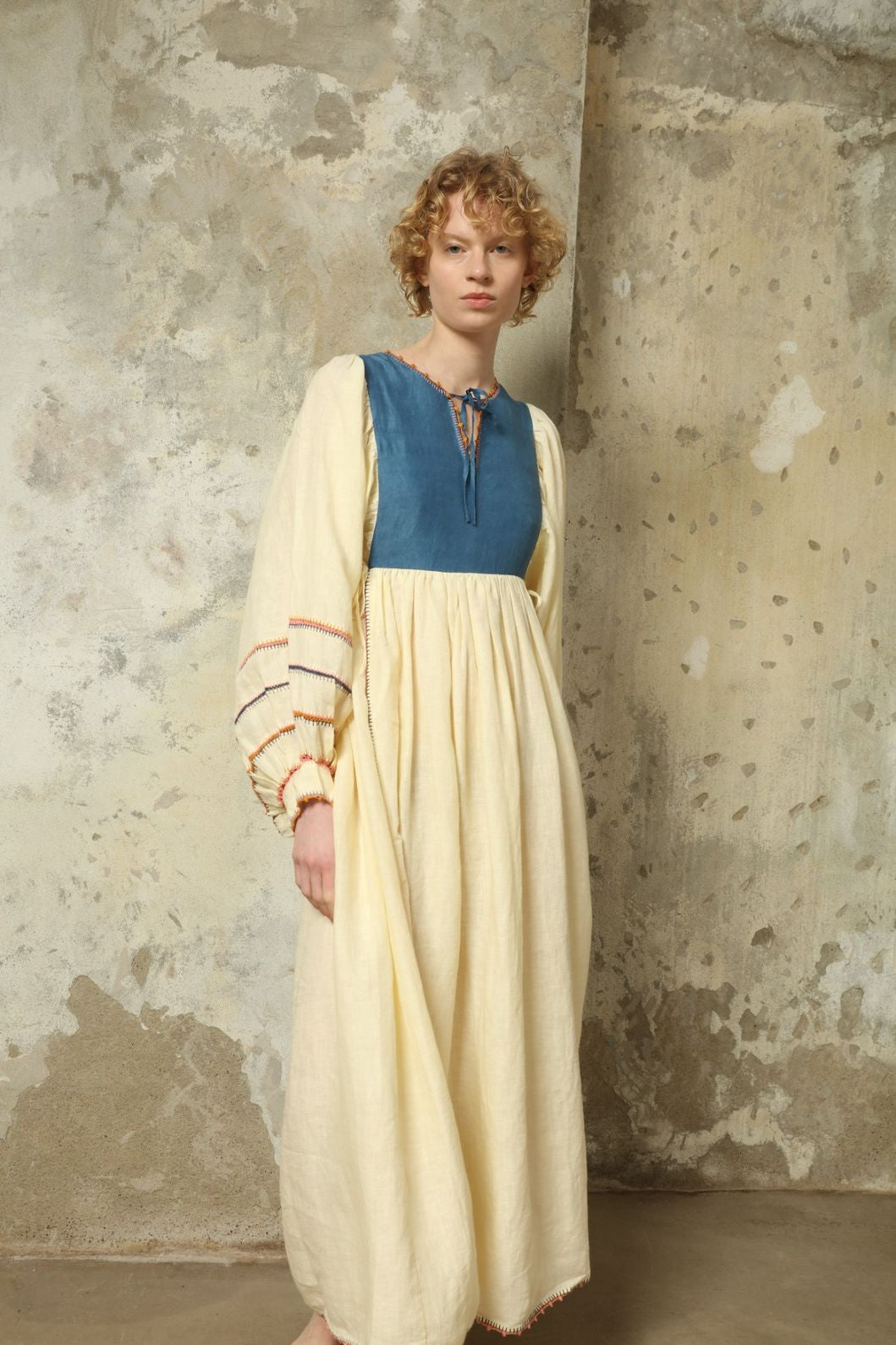 Model is wearing the Serafina Blue Linen Dress by Supernaturae x HONS, crafted in structured linen blended with hand-spun silk, featuring deep indigo botanical dye tones inspired by the sea. This sustainable slow fashion piece includes delicate hand-crochet edges and natural organic variations unique to each garment. Made in small-batch production in Mexico using ancestral techniques, part of the House of Woven Stories selection