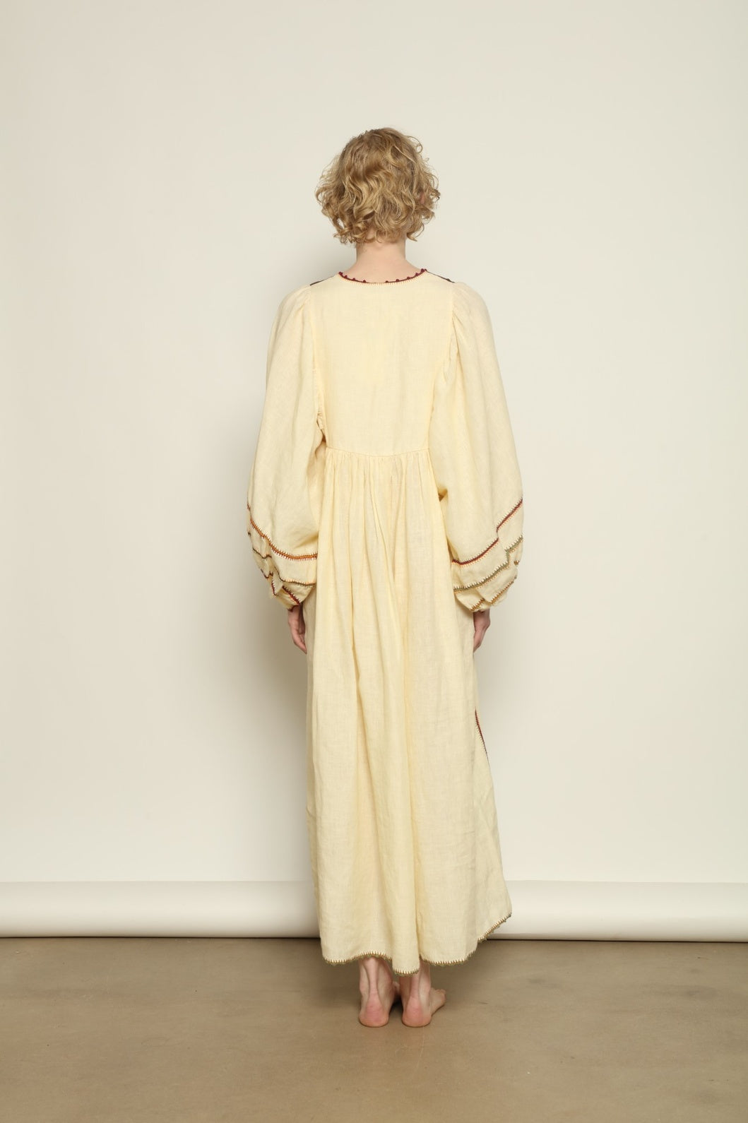 Model is wearing the Serafina Brown Linen Dress by Supernaturae x HONS, crafted in a blend of crisp linen and hand-spun silk with rich earthy botanical dye tones. Featuring a 1970s-inspired kaftan silhouette, hand-crochet edges and adjustable ties, this sustainable slow fashion piece shows natural tonal variations unique to each garment. Made in small-batch production in Mexico using ancestral techniques, part of the House of Woven Stories selection.
