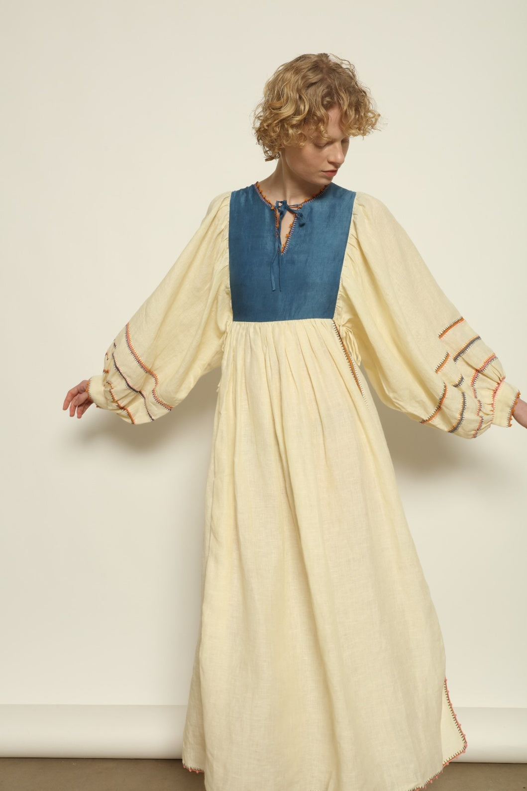 Model is wearing the Serafina Blue Linen Dress by Supernaturae x HONS, crafted in structured linen blended with hand-spun silk, featuring deep indigo botanical dye tones inspired by the sea. This sustainable slow fashion piece includes delicate hand-crochet edges and natural organic variations unique to each garment. Made in small-batch production in Mexico using ancestral techniques, part of the House of Woven Stories selection