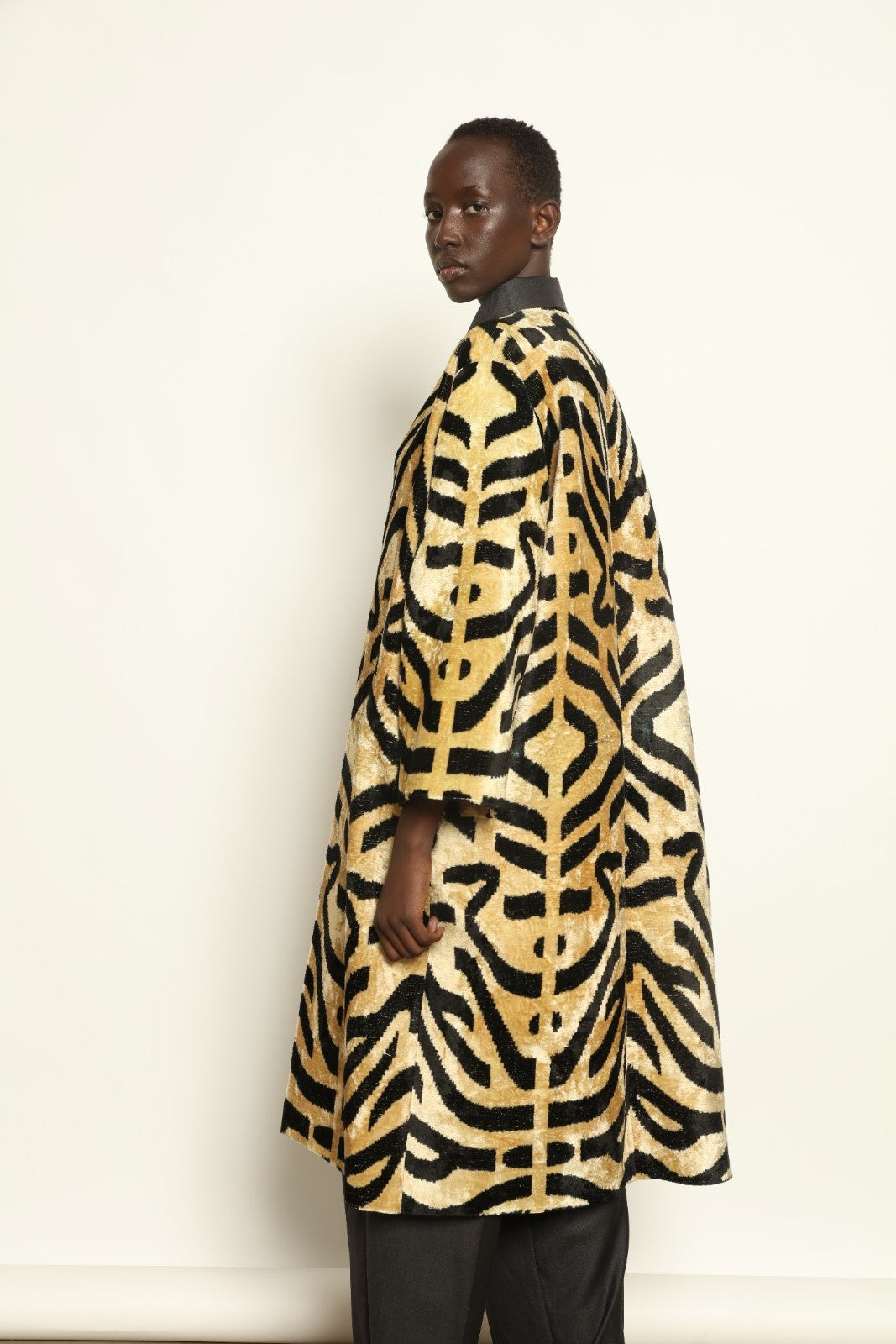 Model is wearing the Serai Ikat Velvet Coat by Aleksandra Viktor, part of House of Woven Stories collection, handwoven Uzbek ikat velvet coat with bold geometric pattern and cobalt lining