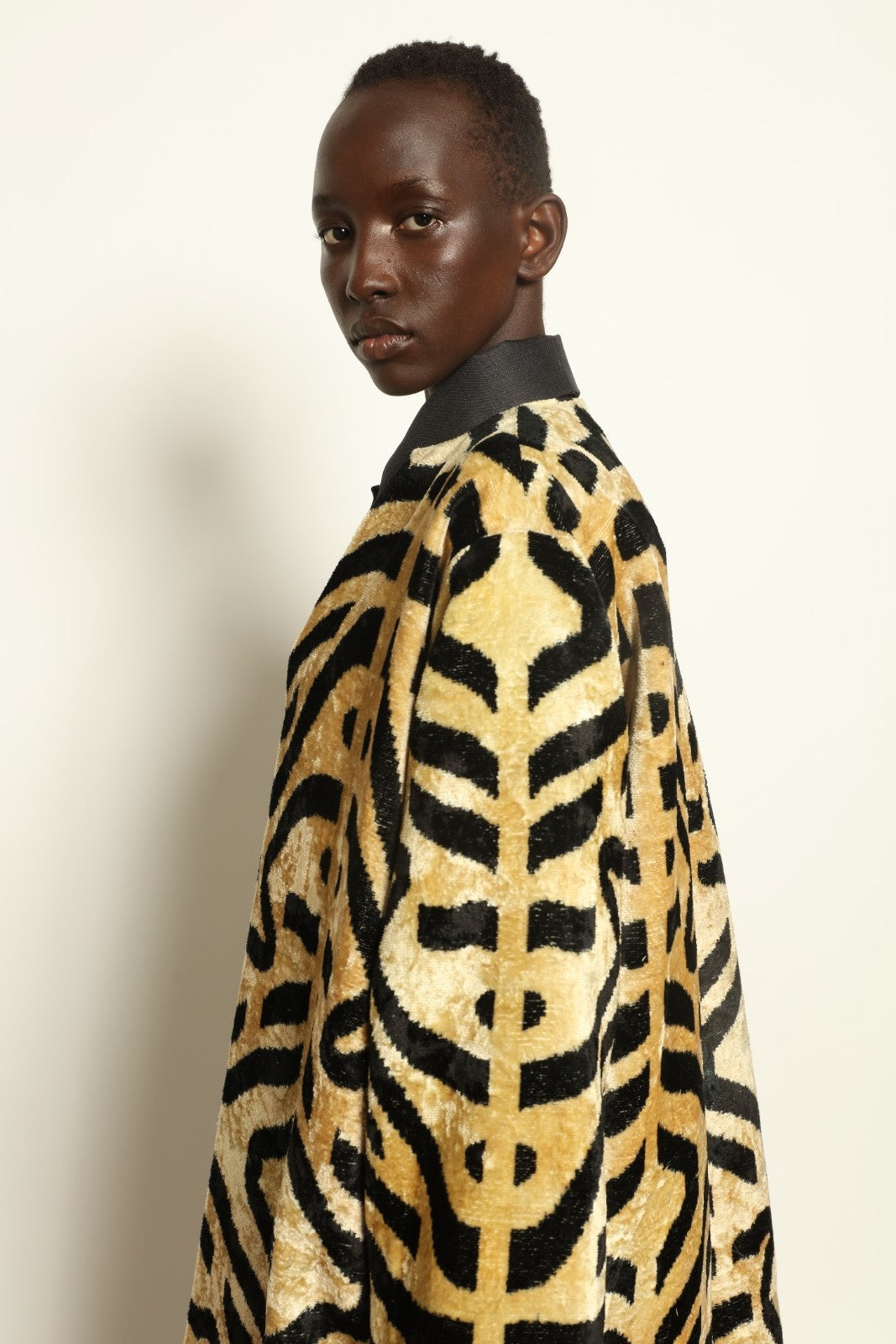 Model is wearing the Serai Ikat Velvet Coat by Aleksandra Viktor, part of House of Woven Stories collection, handwoven Uzbek ikat velvet coat with bold geometric pattern and cobalt lining