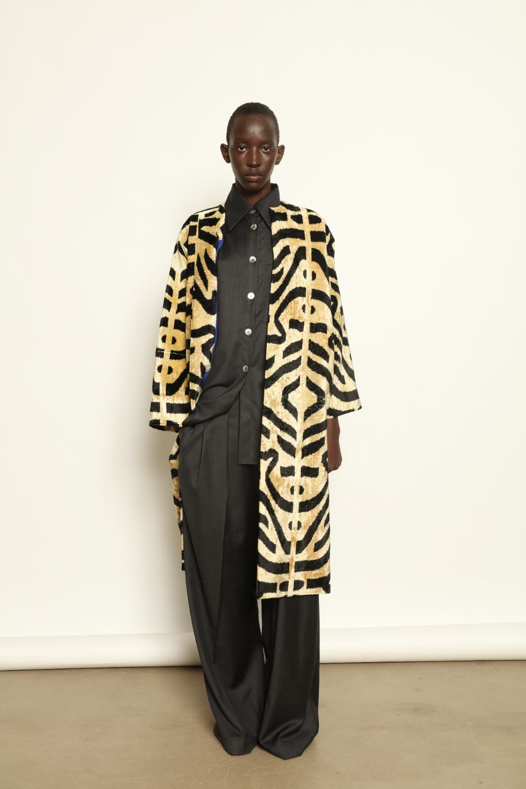 Model is wearing the Serai Ikat Velvet Coat by Aleksandra Viktor, part of House of Woven Stories collection, handwoven Uzbek ikat velvet coat with bold geometric pattern and cobalt lining