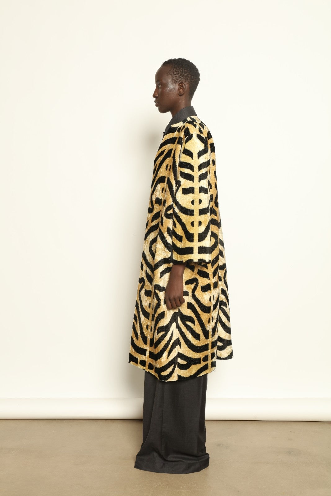 Model is wearing the Serai Ikat Velvet Coat by Aleksandra Viktor, part of House of Woven Stories collection, handwoven Uzbek ikat velvet coat with bold geometric pattern and cobalt lining