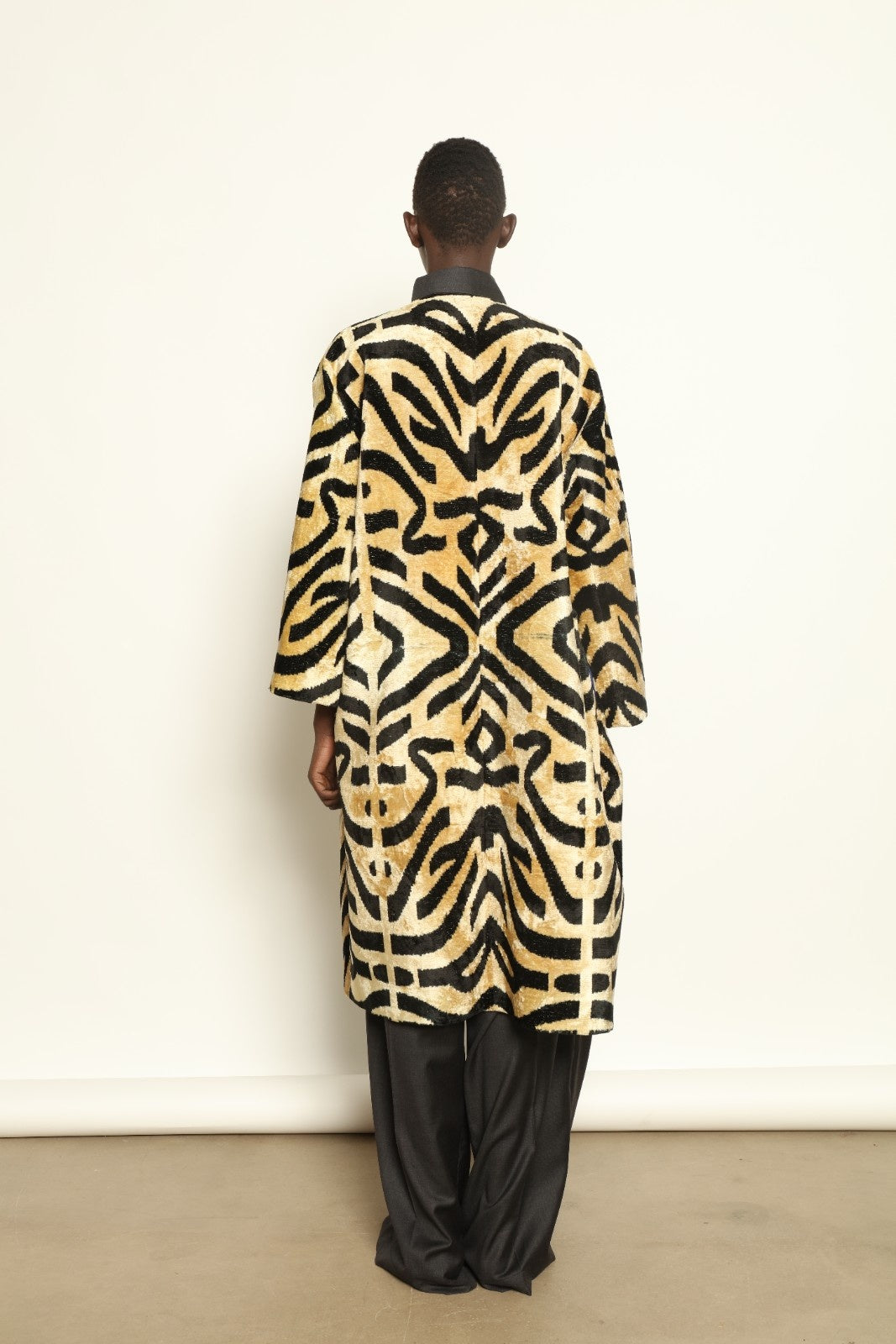 Model is wearing the Serai Ikat Velvet Coat by Aleksandra Viktor, part of House of Woven Stories collection, handwoven Uzbek ikat velvet coat with bold geometric pattern and cobalt lining