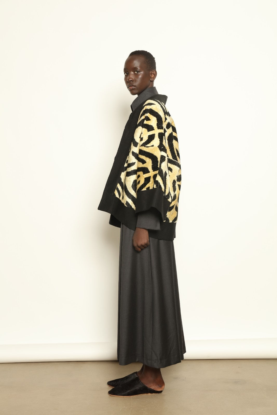 Model is wearing the Serai Ikat Velvet Jacket by Aleksandra Viktor, part of House of Woven Stories collection, handwoven Uzbek ikat velvet jacket with black collar, flowing silhouette, and vibrant blue lining