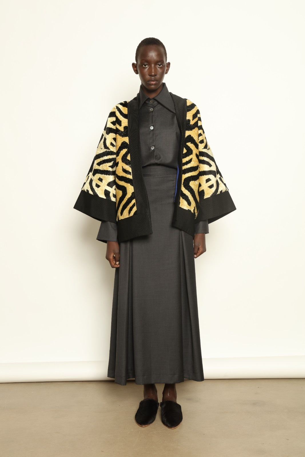 Model is wearing the Serai Ikat Velvet Jacket by Aleksandra Viktor, part of House of Woven Stories collection, handwoven Uzbek ikat velvet jacket with black collar, flowing silhouette, and vibrant blue lining