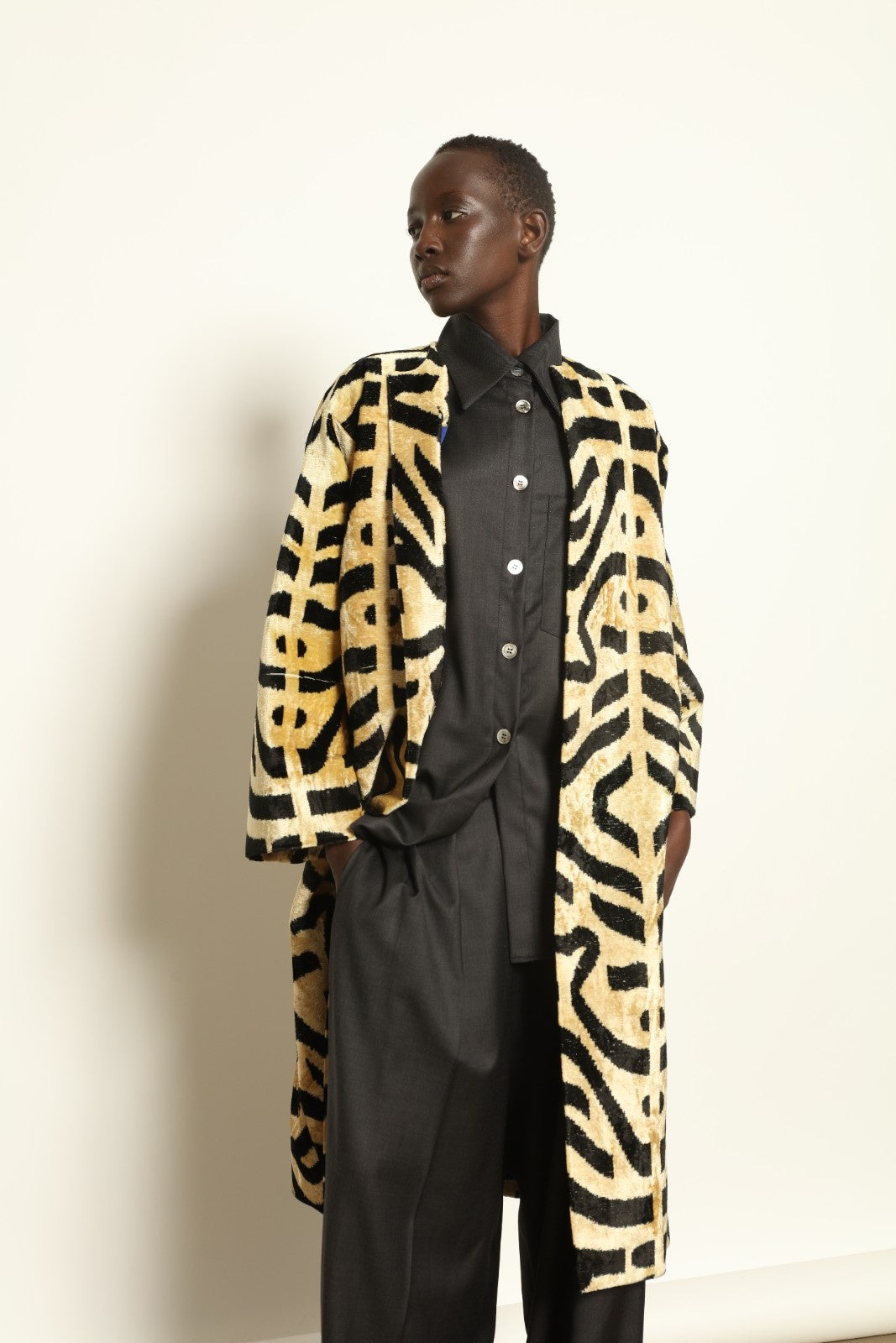 Model is wearing the Serai Ikat Velvet Coat by Aleksandra Viktor, part of House of Woven Stories collection, handwoven Uzbek ikat velvet coat with bold geometric pattern and cobalt lining
