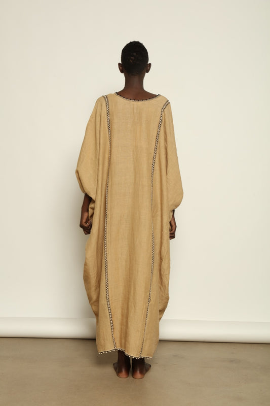 Model is wearing the Thea Beige Linen Dress by Supernaturae x HONS in soft botanical sandy beige linen, featuring a relaxed flowing silhouette, structured breathable fabric and elegant open back design. Part of the House of Woven Stories selection, this ethical slow fashion piece is hand-dyed with natural pigments, showing organic tonal variations.