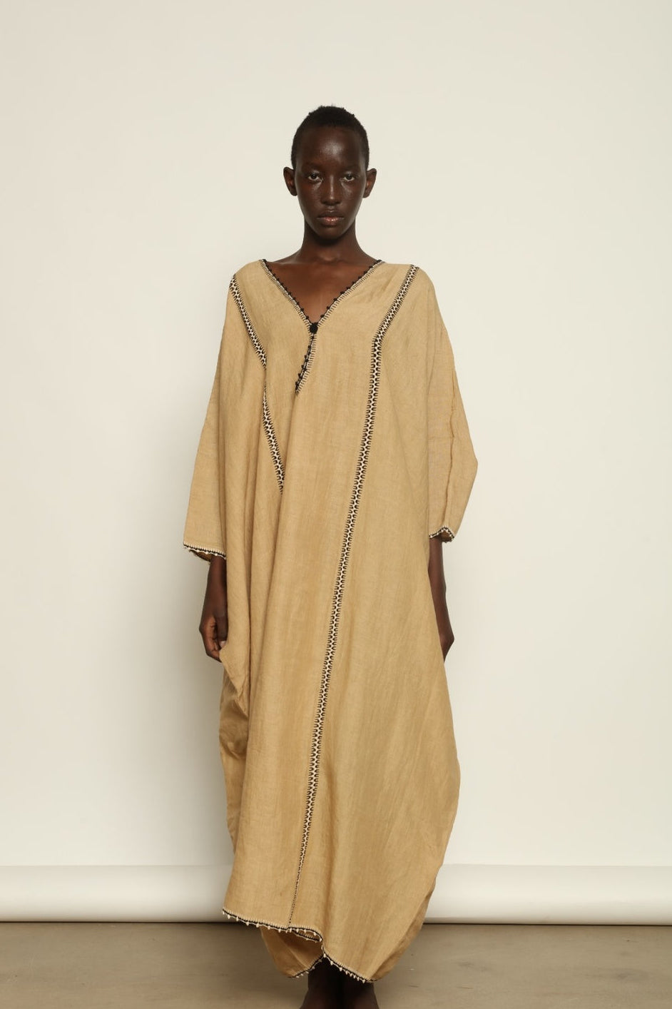 Model is wearing the Thea Beige Linen Dress by Supernaturae x HONS in soft botanical sandy beige linen, featuring a relaxed flowing silhouette, structured breathable fabric and elegant open back design. Part of the House of Woven Stories selection, this ethical slow fashion piece is hand-dyed with natural pigments, showing organic tonal variations.