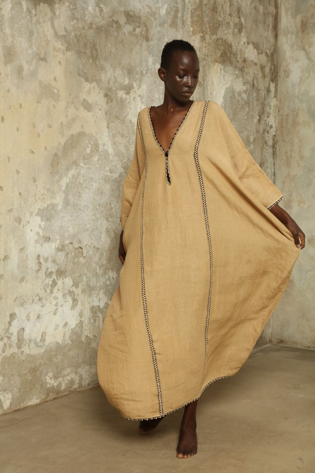 Model is wearing the Thea Beige Linen Dress by Supernaturae x HONS in soft botanical sandy beige linen, featuring a relaxed flowing silhouette, structured breathable fabric and elegant open back design. Part of the House of Woven Stories selection, this ethical slow fashion piece is hand-dyed with natural pigments, showing organic tonal variations.