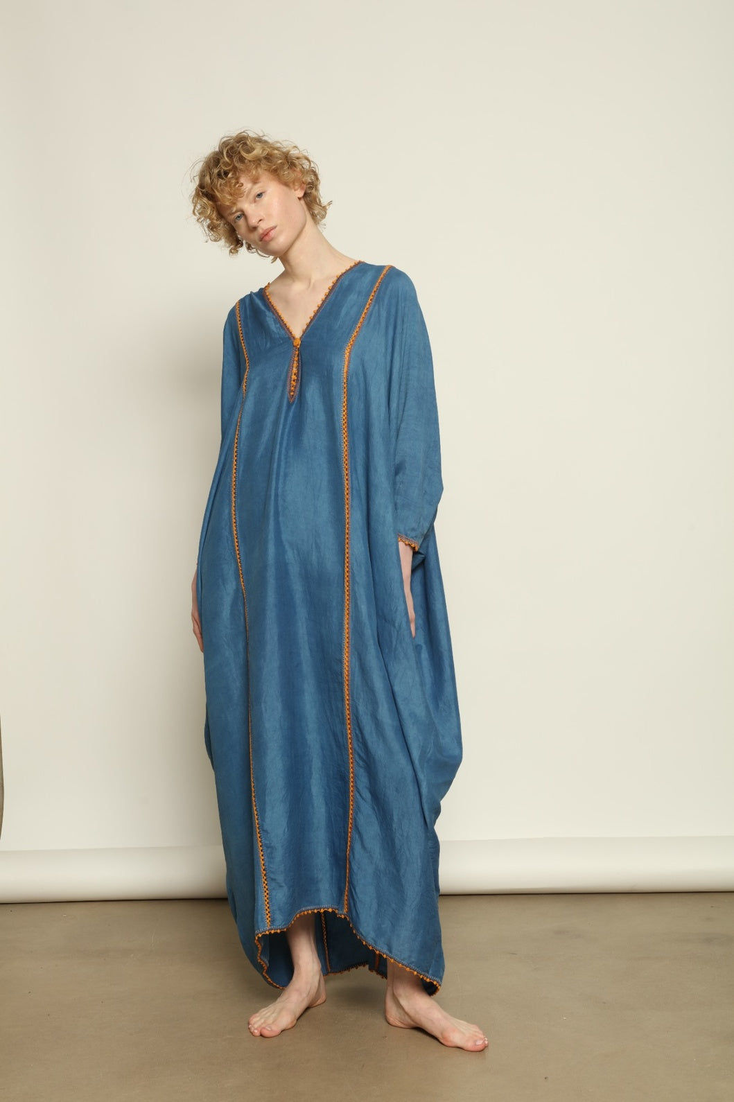 Model is wearing the Thea Blue Silk Dress by Supernaturae x HONS in deep indigo botanical-dyed silk chiffon, featuring a fluid ethereal silhouette and delicate hand-crochet edges. This sustainable slow luxury dress shows natural pigment variations that make each piece unique, crafted in small-batch production in Mexico using ancestral techniques. Part of the House of Woven Stories selection.