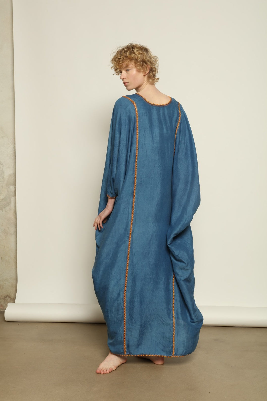 Model is wearing the Thea Blue Silk Dress by Supernaturae x HONS in deep indigo botanical-dyed silk chiffon, featuring a fluid ethereal silhouette and delicate hand-crochet edges. This sustainable slow luxury dress shows natural pigment variations that make each piece unique, crafted in small-batch production in Mexico using ancestral techniques. Part of the House of Woven Stories selection.