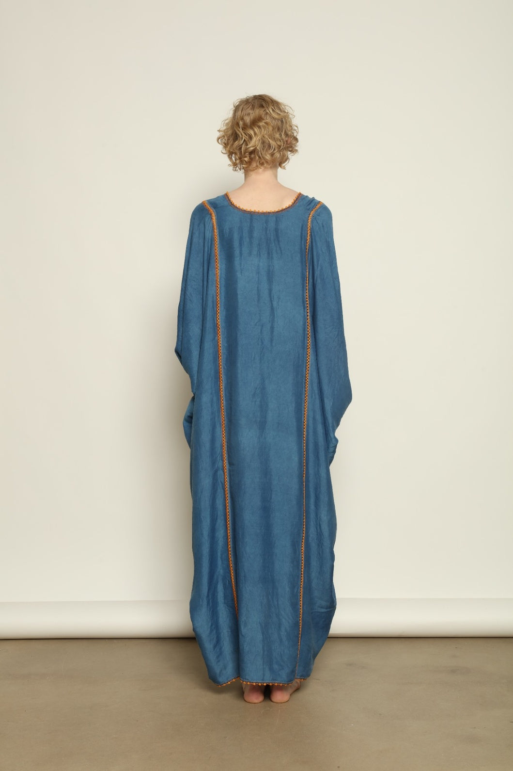 Model is wearing the Thea Blue Silk Dress by Supernaturae x HONS in deep indigo botanical-dyed silk chiffon, featuring a fluid ethereal silhouette and delicate hand-crochet edges. This sustainable slow luxury dress shows natural pigment variations that make each piece unique, crafted in small-batch production in Mexico using ancestral techniques. Part of the House of Woven Stories selection.