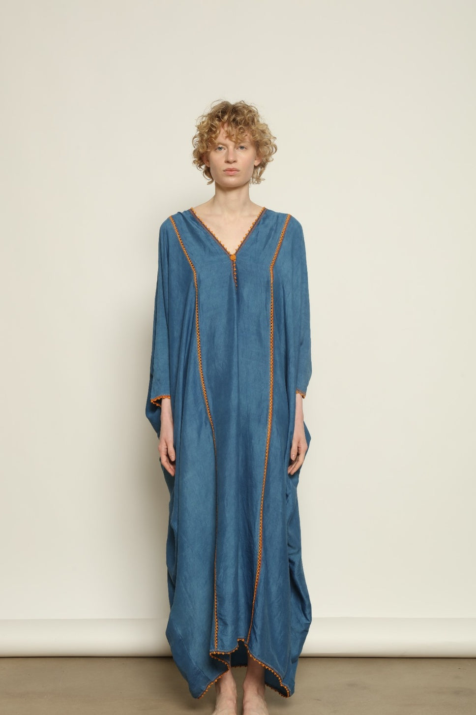 Model is wearing the Thea Blue Silk Dress by Supernaturae x HONS in deep indigo botanical-dyed silk chiffon, featuring a fluid ethereal silhouette and delicate hand-crochet edges. This sustainable slow luxury dress shows natural pigment variations that make each piece unique, crafted in small-batch production in Mexico using ancestral techniques. Part of the House of Woven Stories selection.