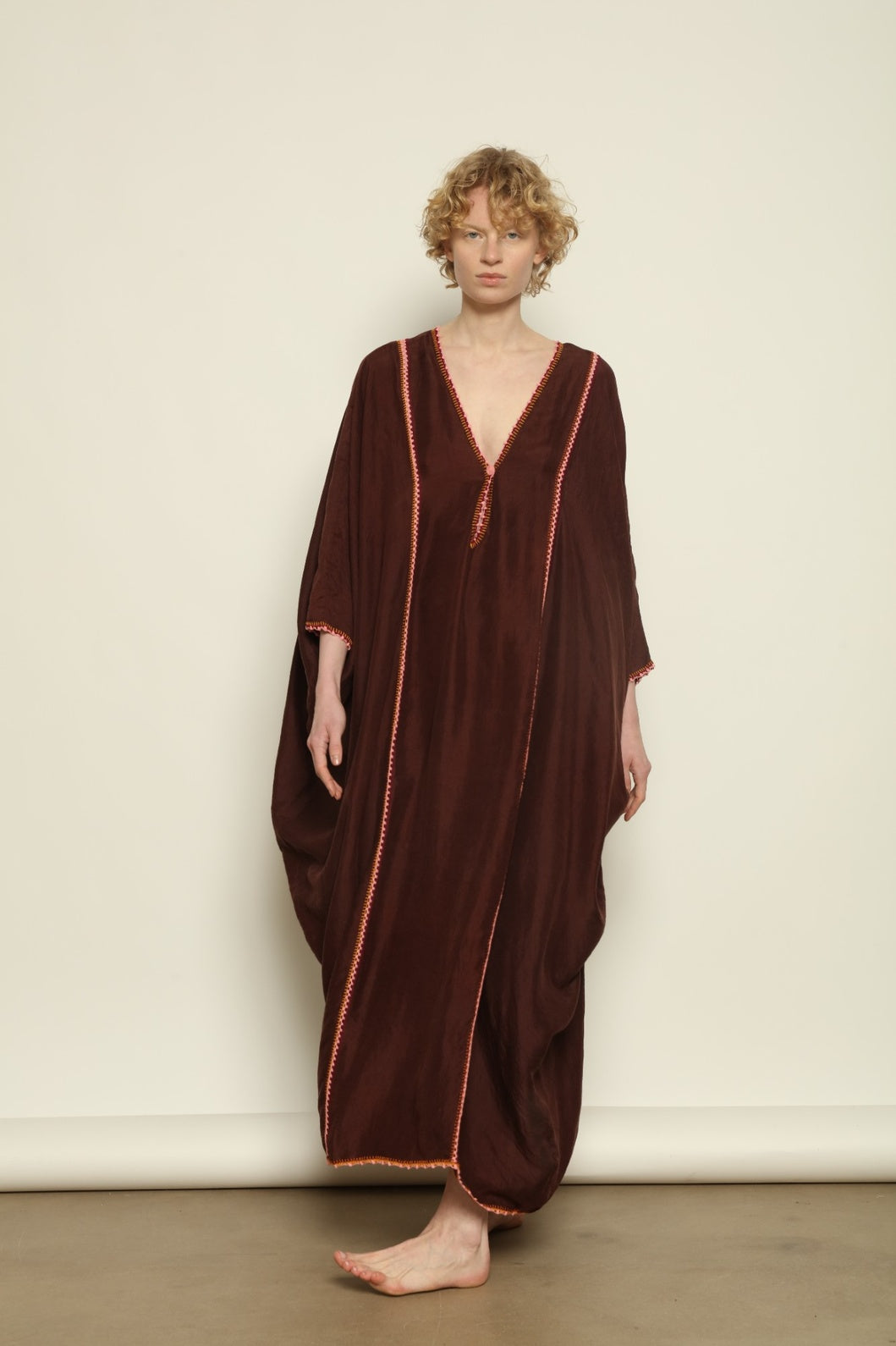 Model is wearing the Thea Brown Silk Dress by Supernaturae x HONS in rich earthy brown handwoven silk from Murshidabad, featuring a soft open back and flowing silhouette. Botanical dyed with natural pigments, this sustainable slow luxury dress shows subtle tonal variations and artisanal craftsmanship, part of the House of Woven Stories selection