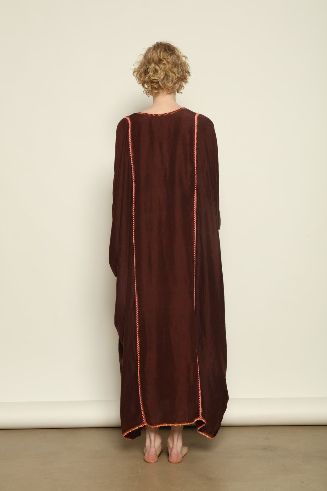 Model is wearing the Thea Brown Silk Dress by Supernaturae x HONS in rich earthy brown handwoven silk from Murshidabad, featuring a soft open back and flowing silhouette. Botanical dyed with natural pigments, this sustainable slow luxury dress shows subtle tonal variations and artisanal craftsmanship, part of the House of Woven Stories selection