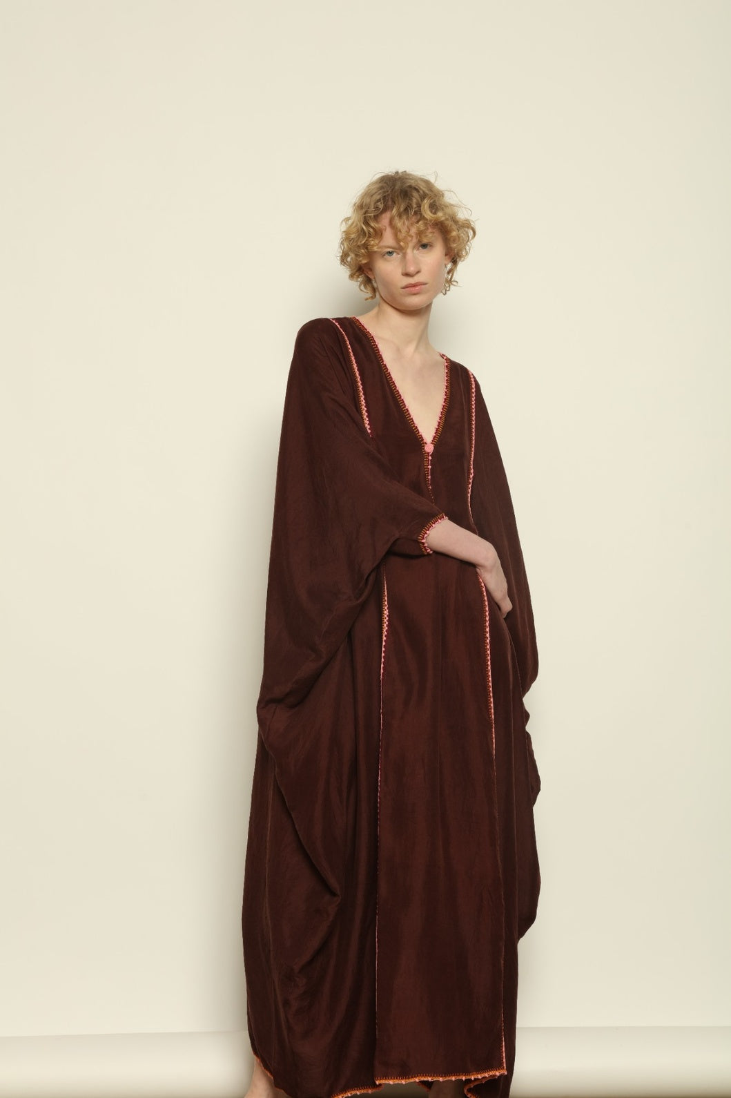 Model is wearing the Thea Brown Silk Dress by Supernaturae x HONS in rich earthy brown handwoven silk from Murshidabad, featuring a soft open back and flowing silhouette. Botanical dyed with natural pigments, this sustainable slow luxury dress shows subtle tonal variations and artisanal craftsmanship, part of the House of Woven Stories selection